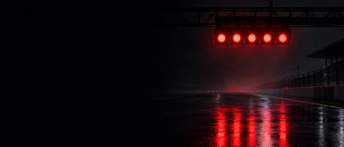 Five red start lights over a wet track at night